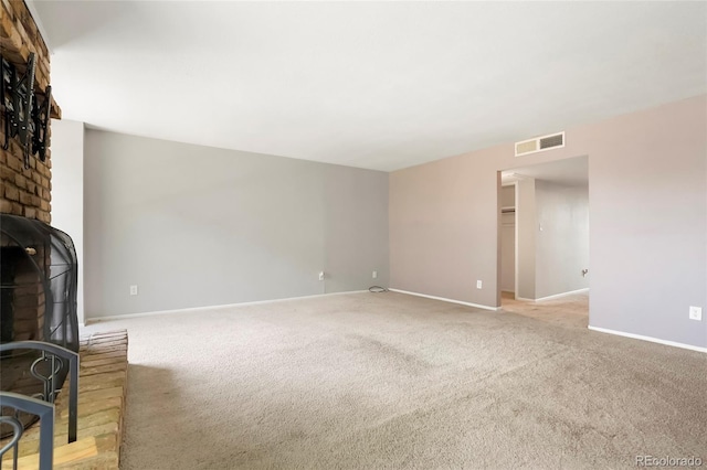 unfurnished living room featuring a wood stove, carpet, baseboards, and visible vents