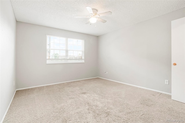 carpeted spare room with a textured ceiling, baseboards, and a ceiling fan