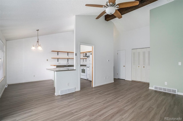 3405 W 16th St Unit 14C, Greeley, CO 80634 - unfurnished living room featuring a ceiling fan, a chandelier, baseboards, wood finished floors, and high vaulted ceiling