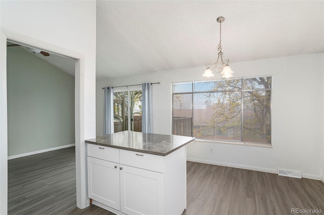 3405 W 16th St Unit 14C, Greeley, CO 80634 - kitchen featuring wood finished floors, a chandelier, vaulted ceiling, white cabinetry, and decorative light fixtures