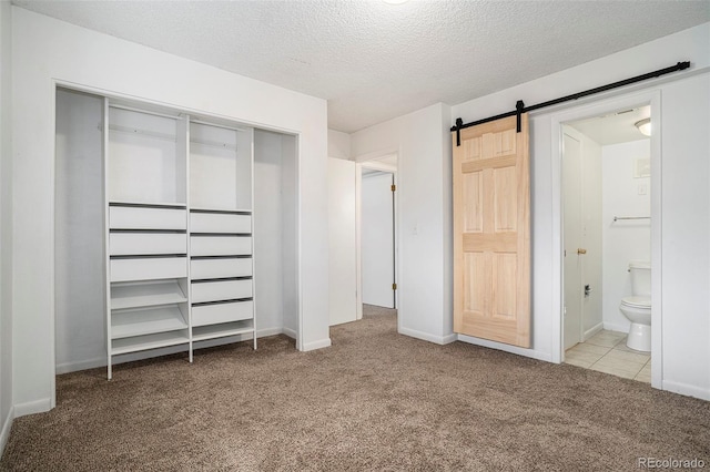 3405 W 16th St Unit 14C, Greeley, CO 80634 - unfurnished bedroom with carpet flooring, a barn door, a closet, a textured ceiling, and ensuite bathroom