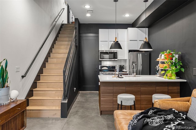 kitchen featuring sink, hanging light fixtures, backsplash, white cabinets, and appliances with stainless steel finishes