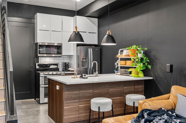 kitchen with decorative backsplash, stainless steel appliances, sink, decorative light fixtures, and white cabinetry