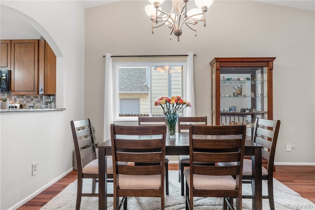 9960 Garland Ln, Broomfield, CO 80021 - dining space with arched walkways, dark wood-type flooring, a chandelier, and baseboards