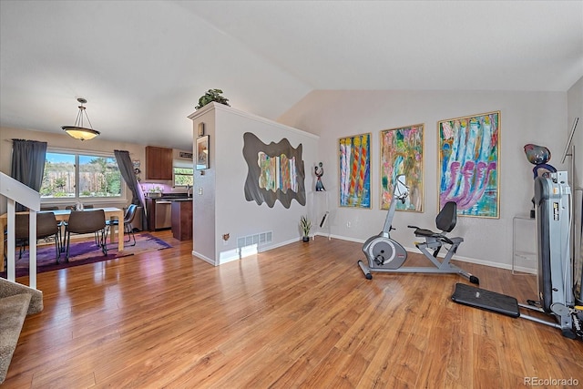 workout area with light hardwood / wood-style floors and lofted ceiling