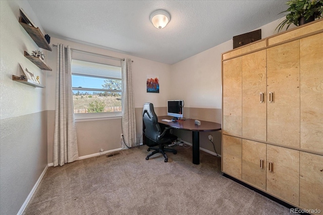 carpeted home office featuring a textured ceiling