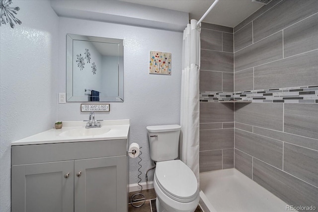 bathroom with a shower with shower curtain, tile patterned floors, vanity, and toilet