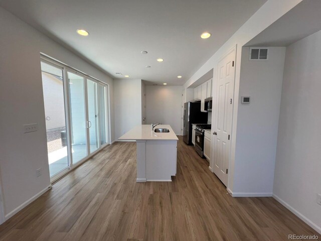 6601 N Netherland St, Aurora, CO 80019 - kitchen with stainless steel appliances, wood finished floors, white cabinets, recessed lighting, and light countertops
