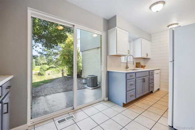 kitchen with decorative backsplash, white appliances, light tile patterned floors, and white cabinets