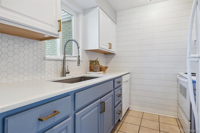 kitchen with white cabinetry, white appliances, light tile patterned floors, blue cabinetry, and sink