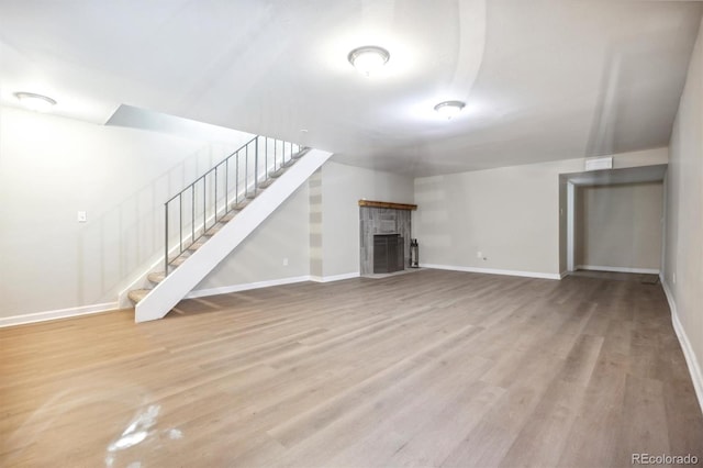 unfurnished living room featuring a tiled fireplace and light hardwood / wood-style floors