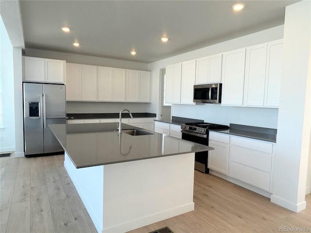 kitchen with stainless steel appliances, sink, a center island with sink, and white cabinets