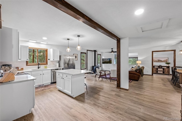 kitchen featuring hanging light fixtures, stainless steel appliances, sink, a kitchen island, and a breakfast bar