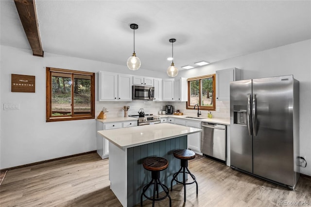 kitchen featuring appliances with stainless steel finishes, a wealth of natural light, pendant lighting, and beamed ceiling