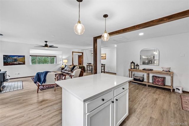 kitchen featuring white cabinets, a center island, light wood-type flooring, ceiling fan, and pendant lighting