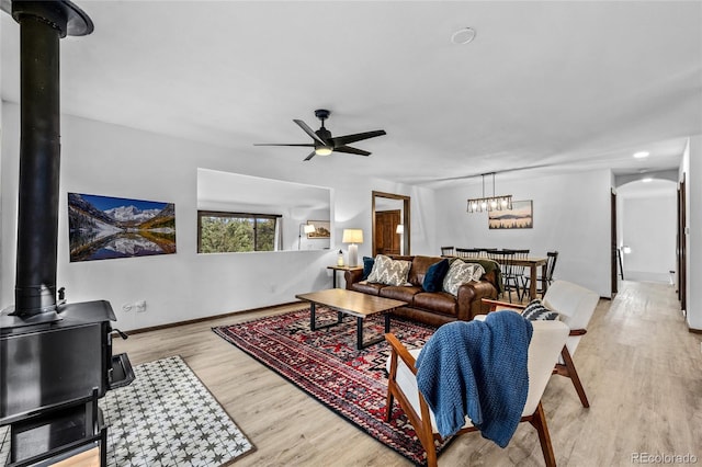 living room featuring ceiling fan, a wood stove, and light hardwood / wood-style flooring