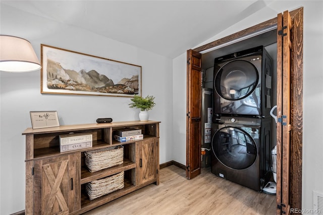 laundry room with light wood-type flooring and stacked washer and dryer