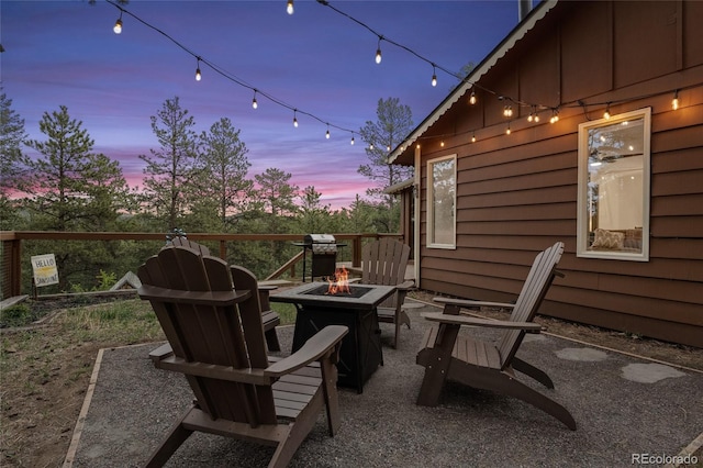 patio terrace at dusk featuring a grill and an outdoor fire pit