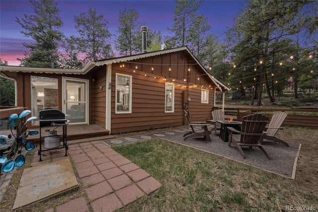 back house at dusk with a patio area and an outdoor fire pit