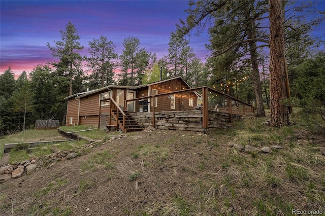 back house at dusk featuring a wooden deck