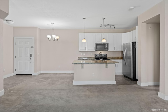 kitchen featuring dark stone counters, a center island with sink, white cabinets, and stainless steel appliances