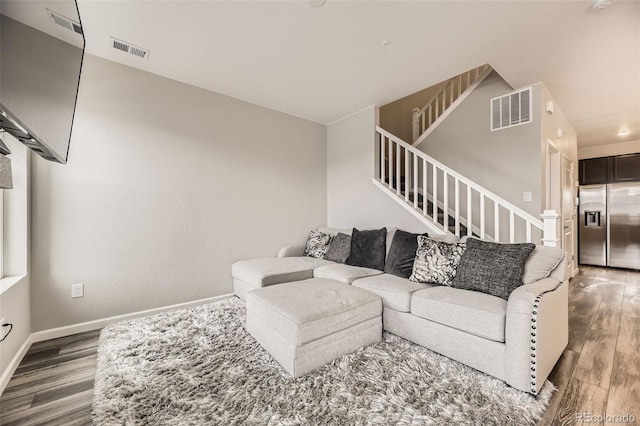 living area featuring visible vents, stairway, baseboards, and wood finished floors