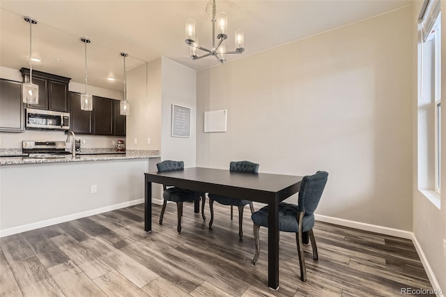 dining area with baseboards, dark wood-style flooring, and a chandelier