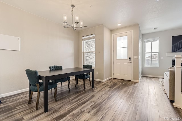 dining room with a notable chandelier, visible vents, baseboards, and wood finished floors