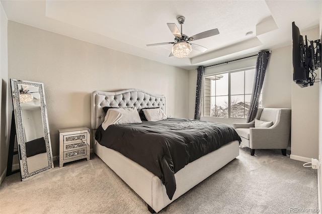 bedroom with a raised ceiling, light colored carpet, baseboards, and ceiling fan