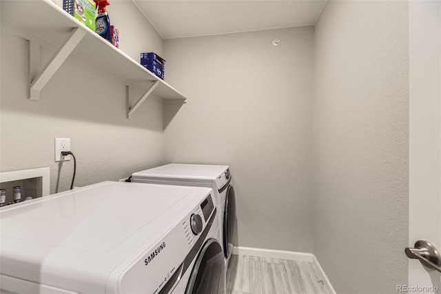 clothes washing area with baseboards, separate washer and dryer, wood finished floors, and laundry area