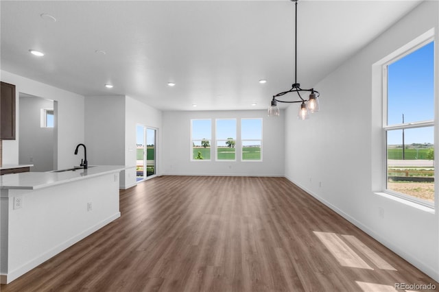 unfurnished living room featuring a sink, wood finished floors, recessed lighting, and baseboards