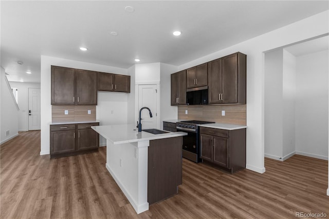 kitchen with a sink, stainless steel gas stove, dark wood-style floors, baseboards, and tasteful backsplash