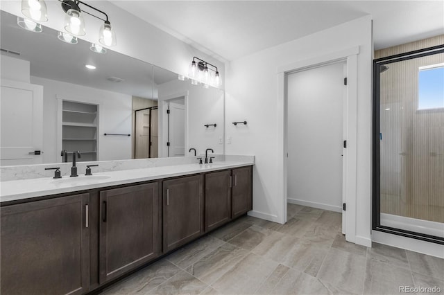 full bathroom featuring a shower stall, double vanity, and baseboards