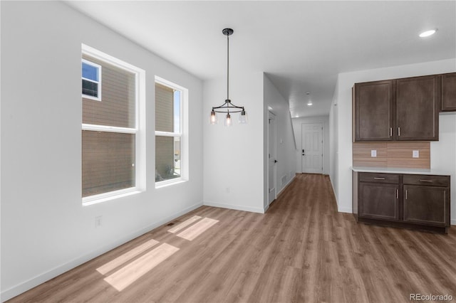 unfurnished dining area with light wood-type flooring, baseboards, and recessed lighting