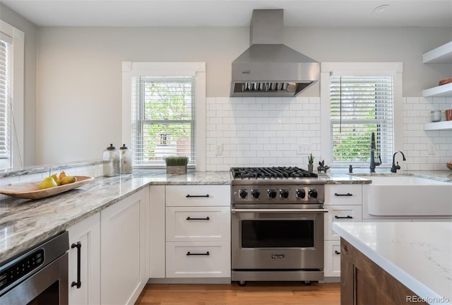 401 S Williams St, Denver, CO 80209 - kitchen featuring luxury stove, wall chimney range hood, a sink, white cabinetry, and light stone counters