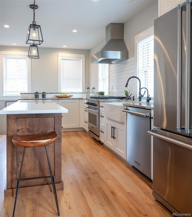 401 S Williams St, Denver, CO 80209 - kitchen with appliances with stainless steel finishes, extractor fan, light wood finished floors, white cabinets, and healthy amount of natural light