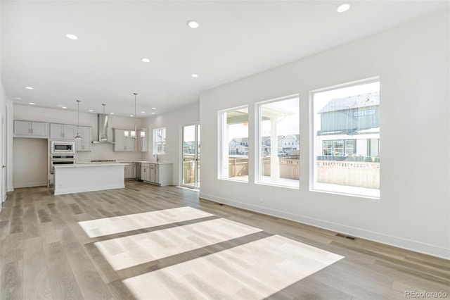 unfurnished living room with a notable chandelier and light hardwood / wood-style floors