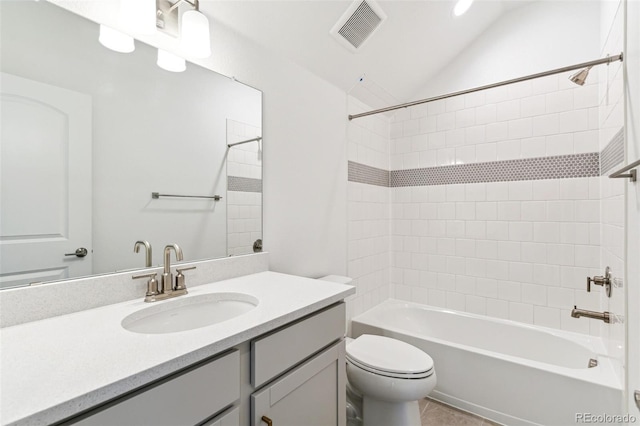 full bathroom featuring vanity, toilet, tiled shower / bath combo, tile patterned flooring, and vaulted ceiling