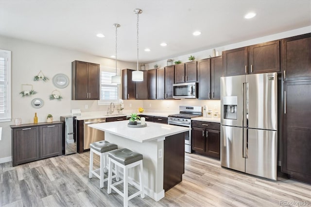 2395 S Troy Ct, Aurora, CO 80014 - kitchen featuring appliances with stainless steel finishes, dark brown cabinetry, light countertops, light wood finished floors, and recessed lighting