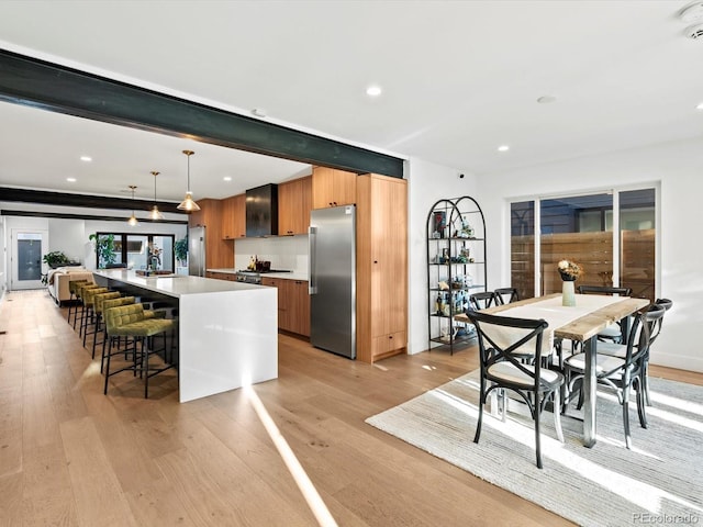 1612 Wolff St, Denver, CO 80204 - kitchen with stainless steel fridge, modern cabinets, light wood-style flooring, a kitchen breakfast bar, and recessed lighting