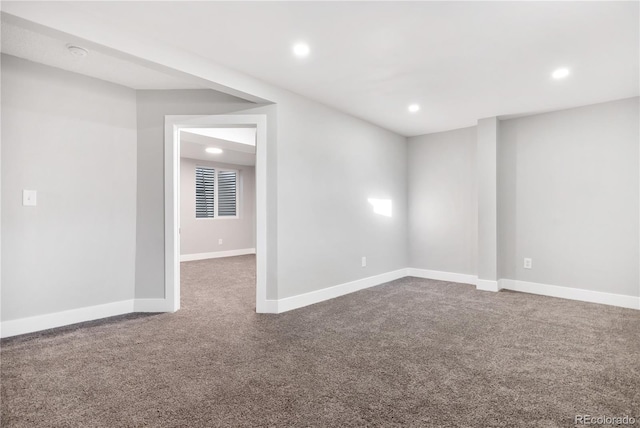 spare room with dark colored carpet, recessed lighting, and baseboards