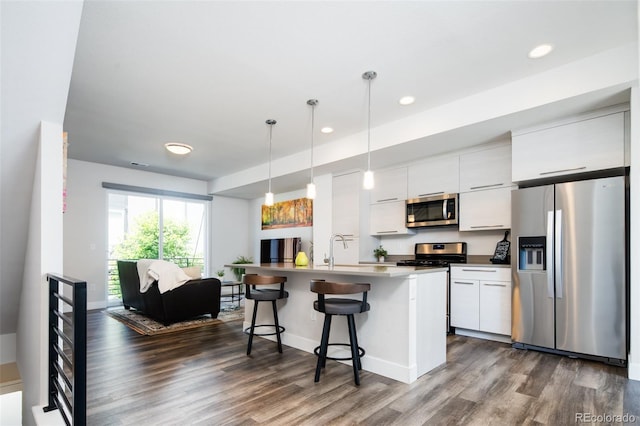 5630 W 11th Pl, Lakewood, CO 80214 - kitchen with stainless steel appliances, dark wood-style flooring, a kitchen bar, white cabinetry, and a kitchen island with sink