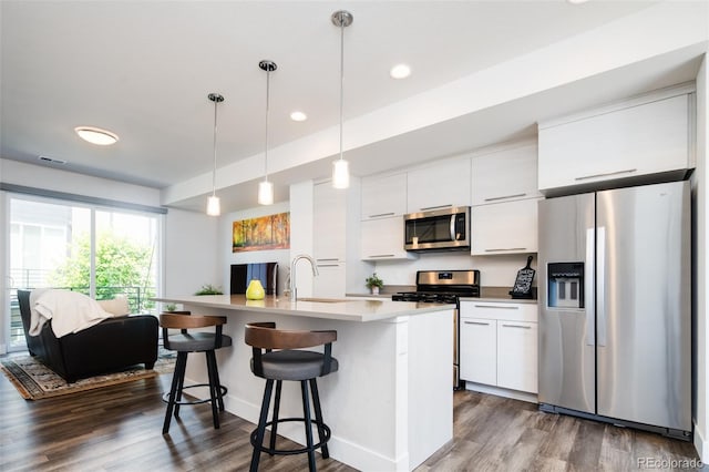 5630 W 11th Pl, Lakewood, CO 80214 - kitchen featuring appliances with stainless steel finishes, a sink, dark wood finished floors, a kitchen bar, and recessed lighting