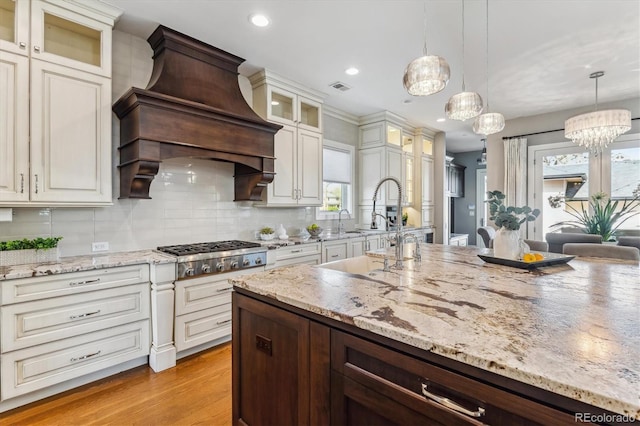 2600 S Adams St, Denver, CO 80210 - kitchen featuring stainless steel gas cooktop, light wood-type flooring, wall chimney exhaust hood, recessed lighting, and light stone counters