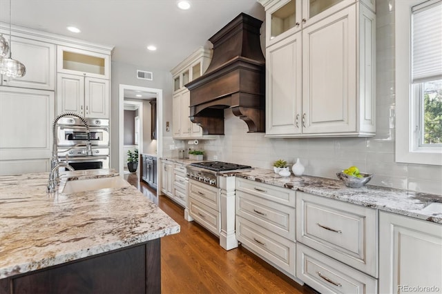 2600 S Adams St, Denver, CO 80210 - kitchen with custom exhaust hood, appliances with stainless steel finishes, decorative backsplash, dark wood-style floors, and recessed lighting
