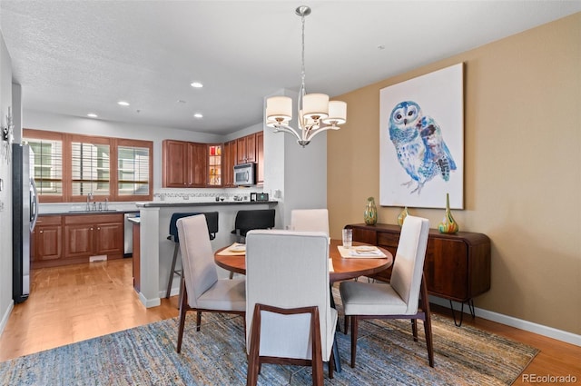 dining space featuring sink, light hardwood / wood-style floors, and an inviting chandelier