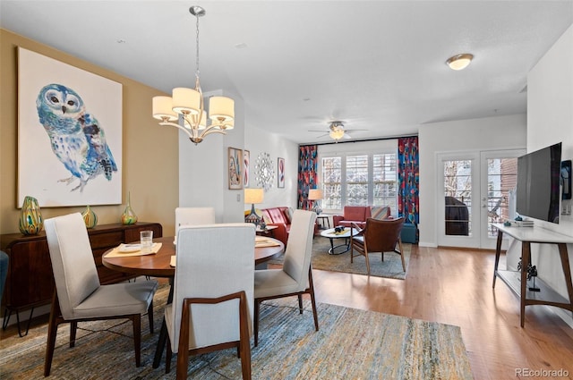 dining area with ceiling fan with notable chandelier and hardwood / wood-style floors