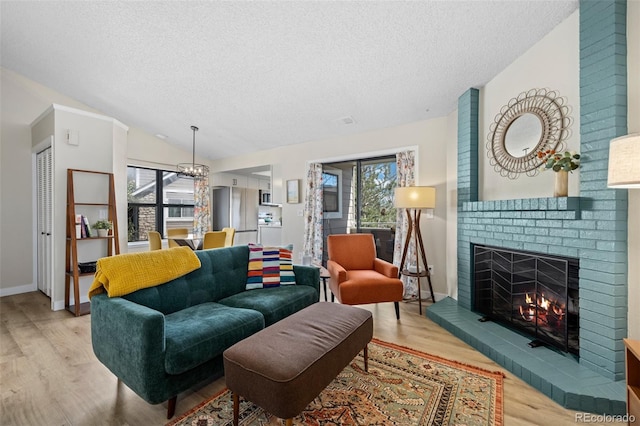 8378 S Upham Way Unit B305, Littleton, CO 80128 - living room with a textured ceiling, light wood-type flooring, a brick fireplace, lofted ceiling, and a chandelier