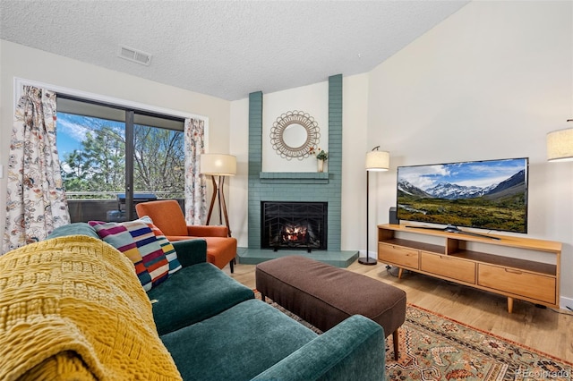 8378 S Upham Way Unit B305, Littleton, CO 80128 - living area featuring wood finished floors, a brick fireplace, a textured ceiling, and vaulted ceiling