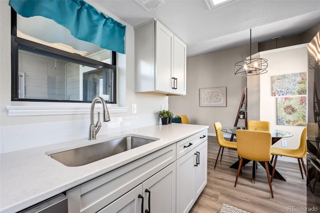 8378 S Upham Way Unit B305, Littleton, CO 80128 - kitchen with light wood-type flooring, light countertops, white cabinets, and a textured ceiling